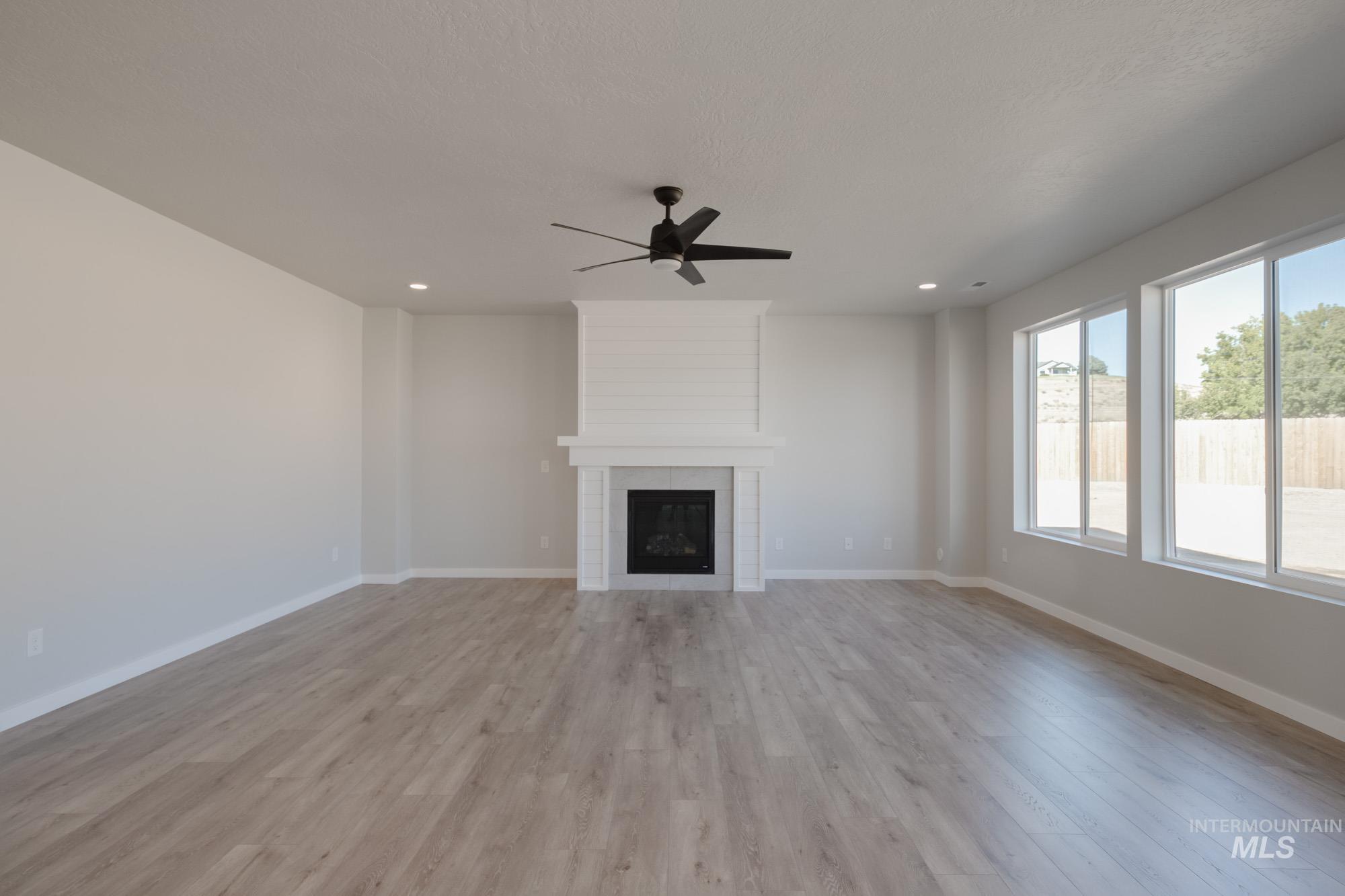 13708 Judson Street Caldwell, ID 83607 - Photo 11 of 32 Unfurnished living room with light wood finished floors, a fireplace, recessed lighting, and a ceiling fan