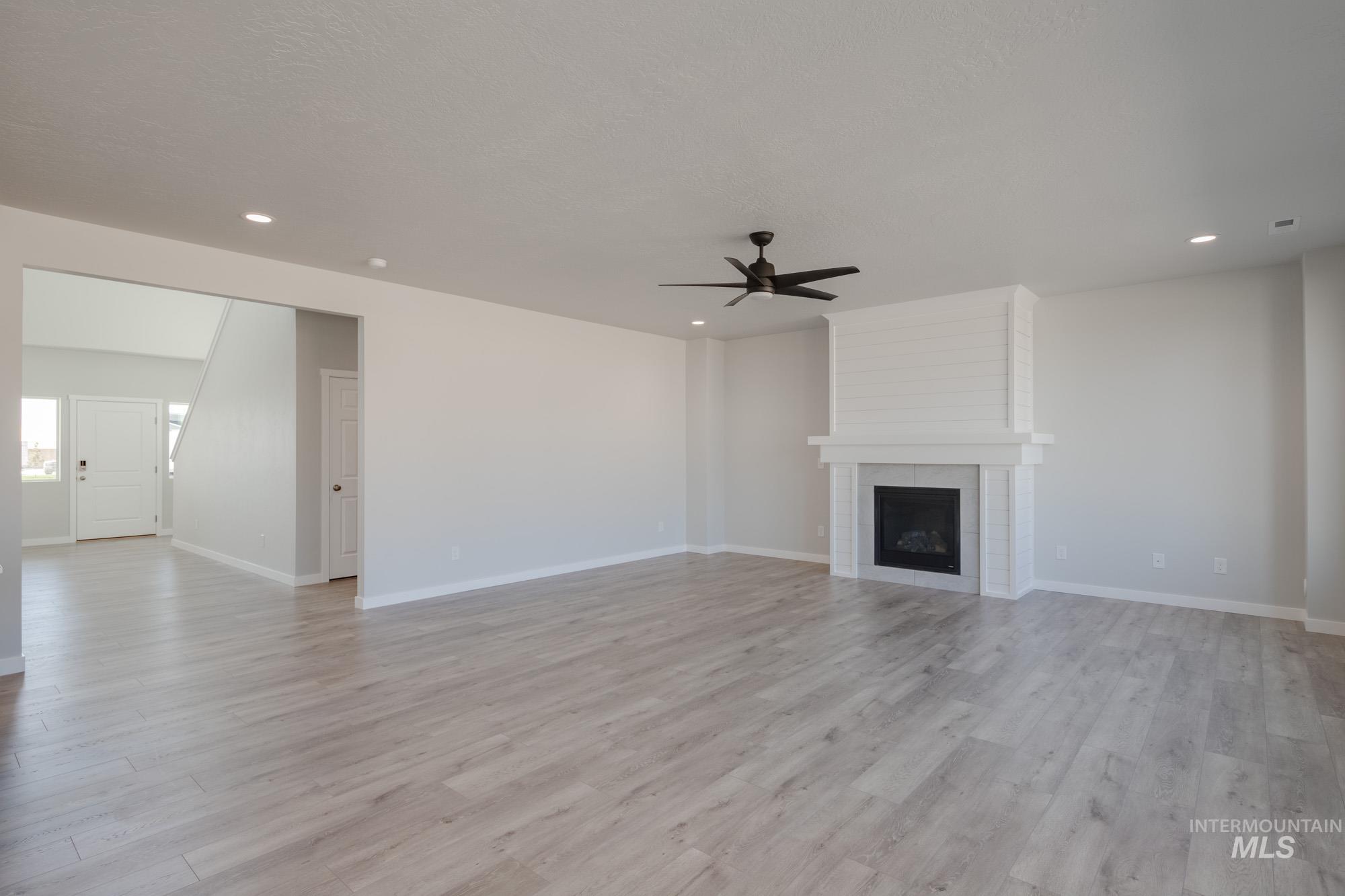 13708 Judson Street Caldwell, ID 83607 - Photo 12 of 32 Unfurnished living room with a large fireplace, light wood finished floors, ceiling fan, and recessed lighting