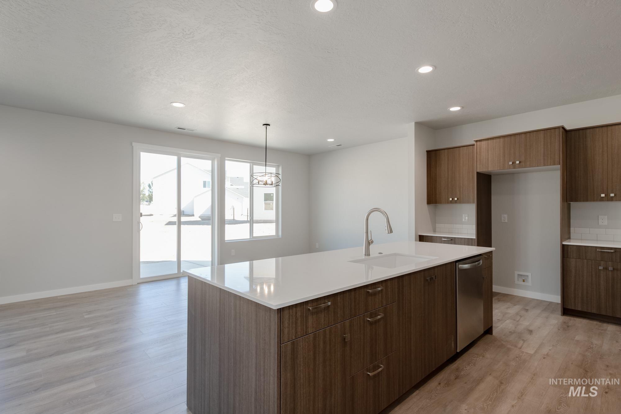 13708 Judson Street Caldwell, ID 83607 - Photo 9 of 32 Kitchen featuring light wood-style floors, a chandelier, a kitchen island with sink, modern cabinets, and pendant lighting