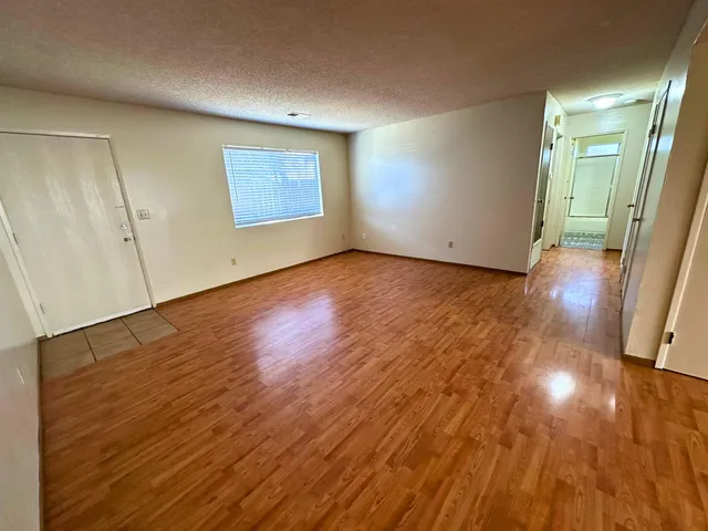 a view of empty room with wooden floor and fan