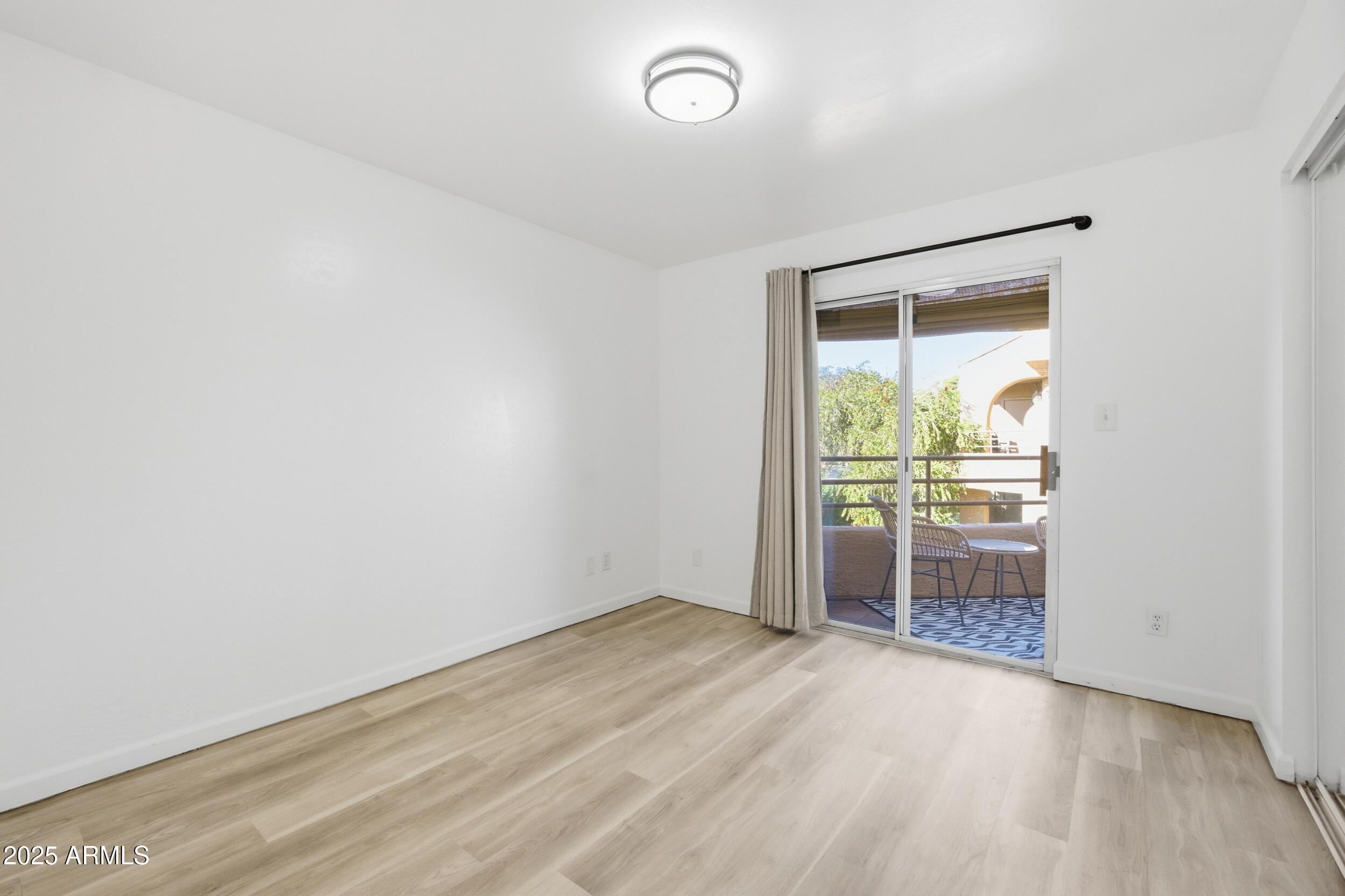 3845 East Greenway Road, Unit 230 Phoenix, AZ 85032 - Photo 8 of 37 an empty room with wooden floor and windows