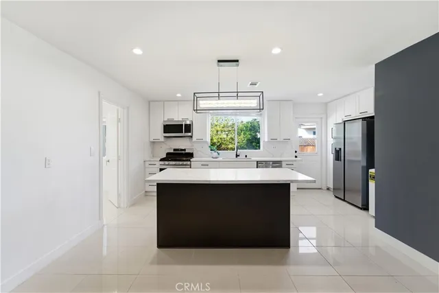 a view of kitchen with stainless steel appliances granite countertop a sink and refrigerator