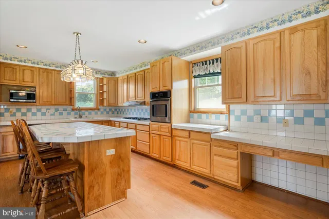 a large kitchen with granite countertop a stove a sink a window and dining table