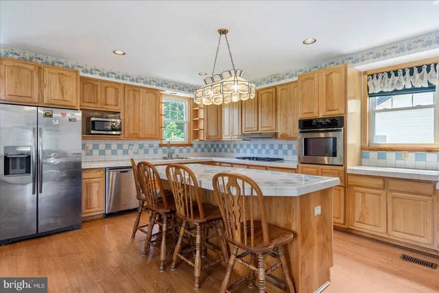 a kitchen with stainless steel appliances granite countertop a stove top oven a sink a dining table and chairs