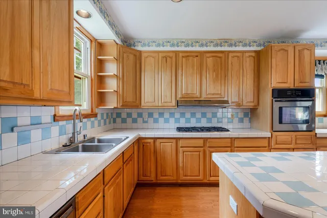a kitchen with stainless steel appliances granite countertop a sink a stove counter space and cabinets