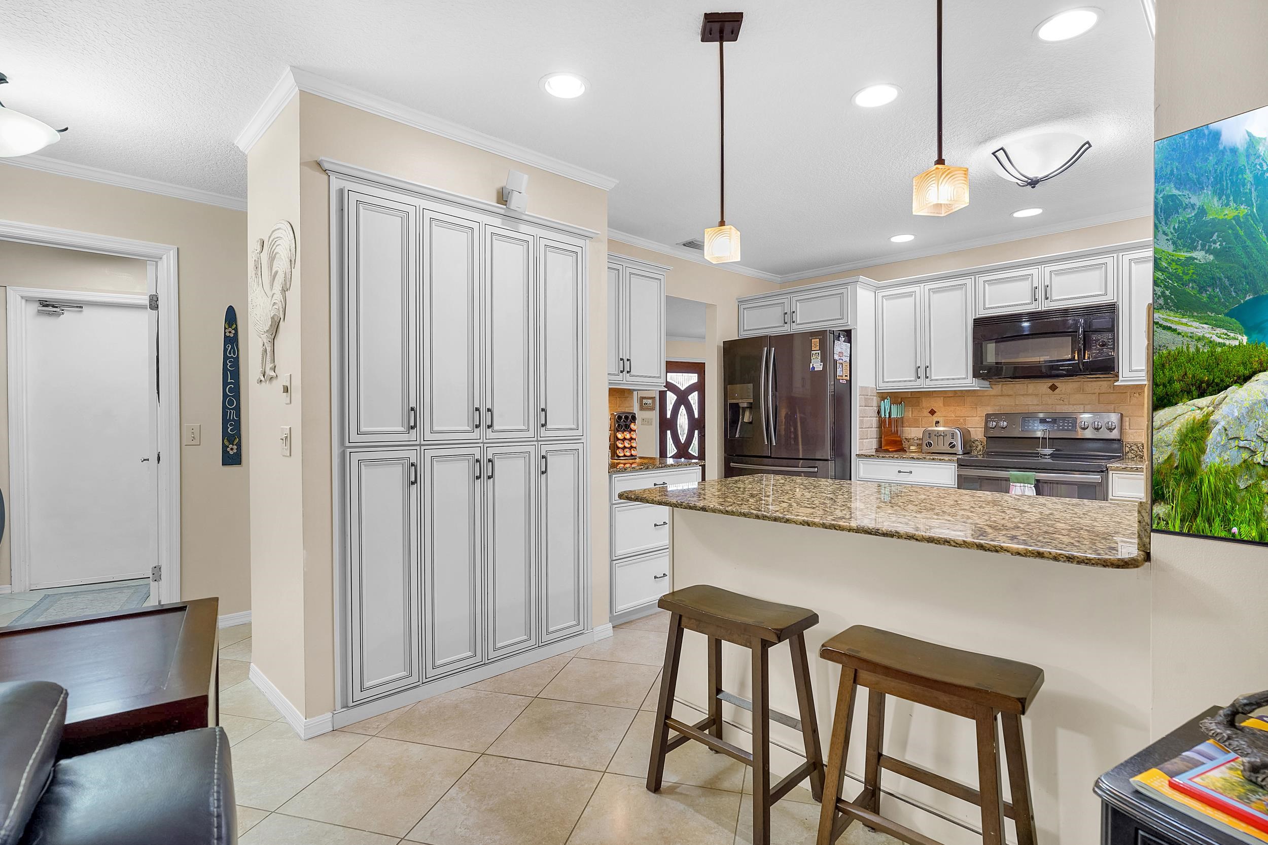 4 Calusa Court Palm Coast, FL 32137 - Photo 15 of 51 Kitchen with a breakfast bar area, ornamental molding, appliances with stainless steel finishes, decorative light fixtures, and dark stone countertops
