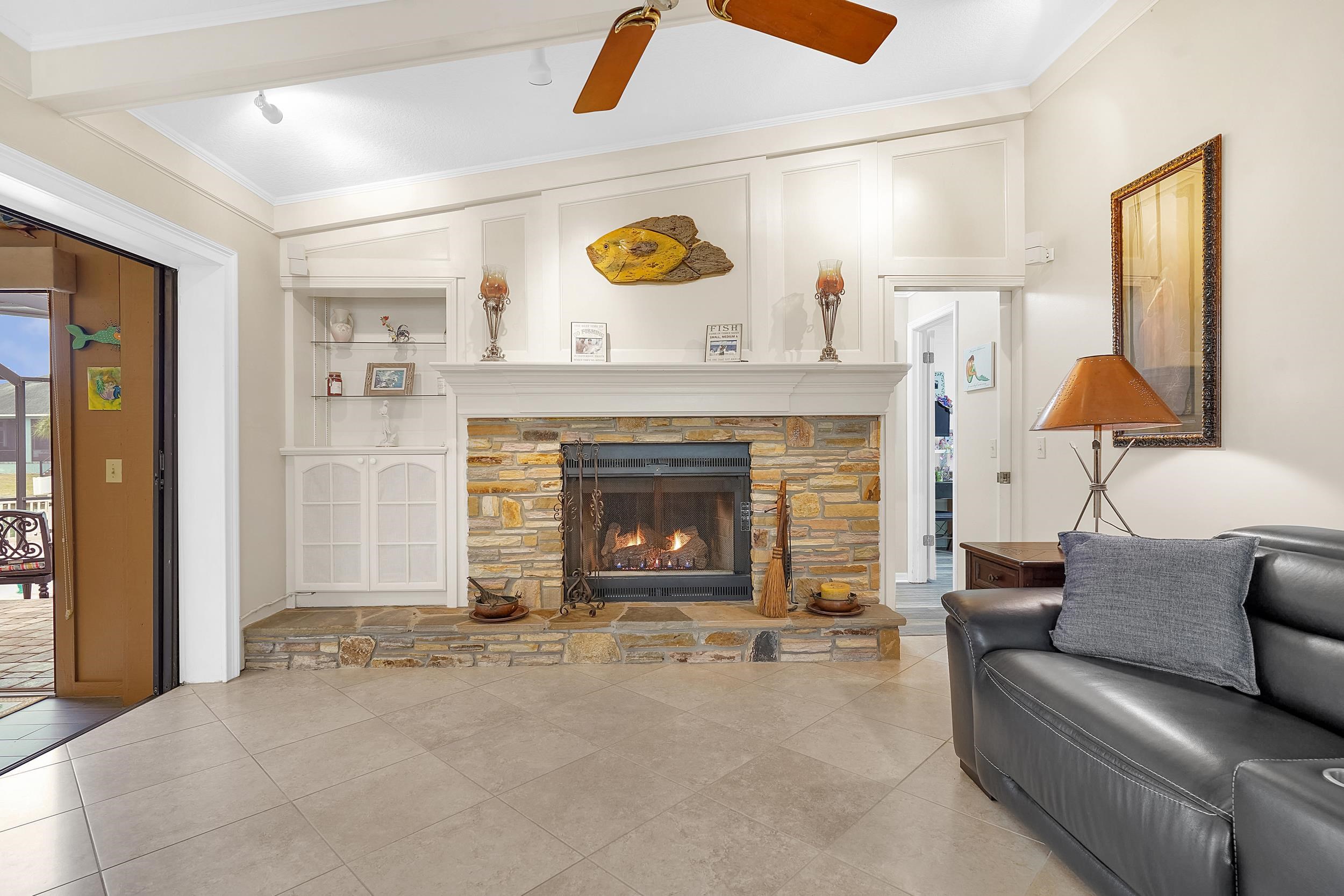 4 Calusa Court Palm Coast, FL 32137 - Photo 8 of 51 Tiled living room featuring a stone fireplace, ornamental molding, built in shelves, and a ceiling fan