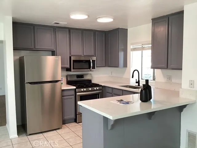 a kitchen with stainless steel appliances a refrigerator a sink a stove a microwave and cabinets