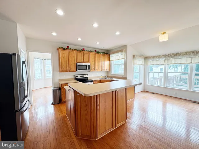 a kitchen with stainless steel appliances granite countertop a stove a sink a refrigerator and a center island with wooden floor