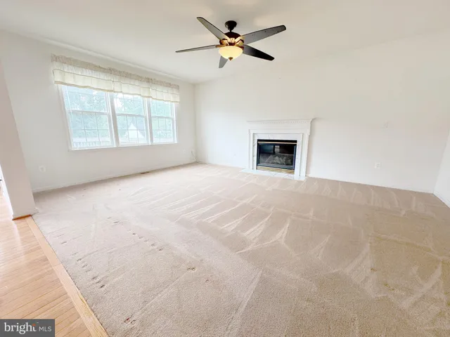 an empty room with windows and ceiling fan