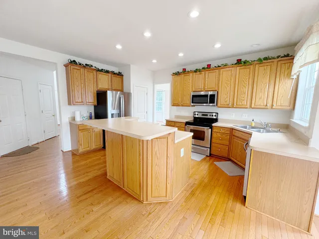 a kitchen with kitchen island granite countertop a stove top oven a sink a counter top space and cabinets