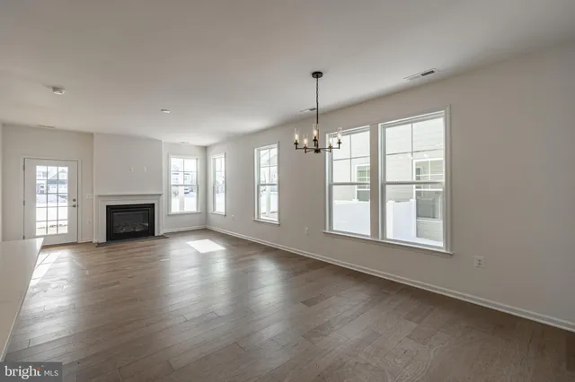 an empty room with wooden floor fireplace and windows