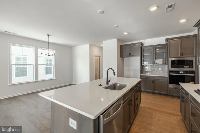 a kitchen with stainless steel appliances granite countertop a sink a oven a counter space and cabinets