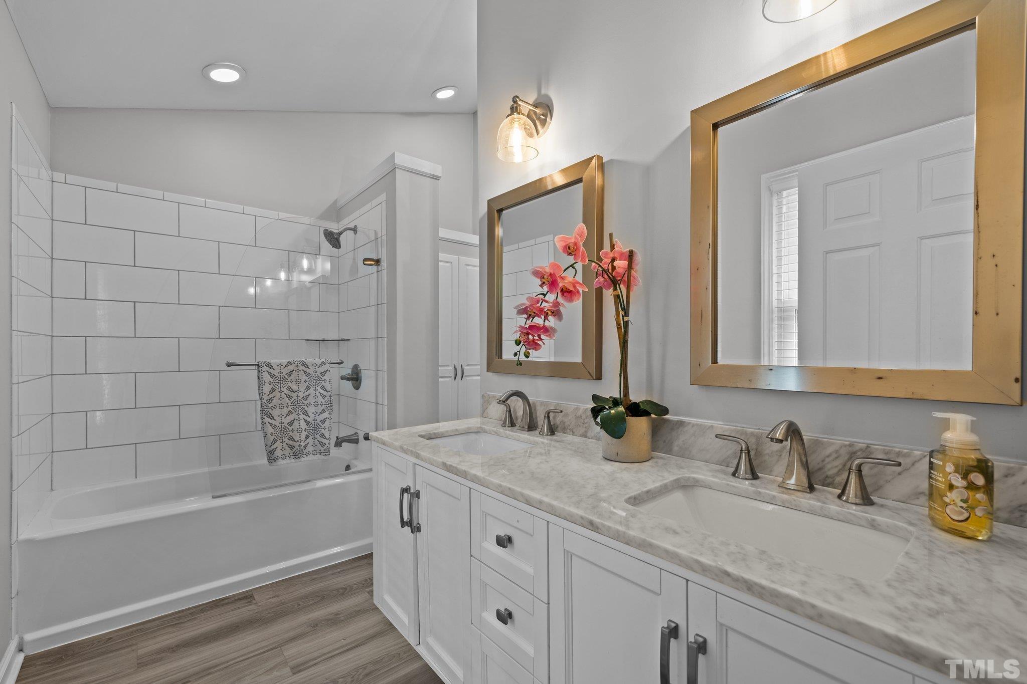 12028 North Exeter Way Raleigh, NC 27613 - Photo 30 of 48 a bathroom with double vanity sinks a mirror and a bath tub