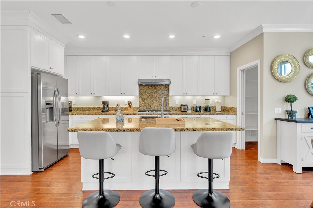 75 Gardenstone Path Irvine, CA 92620 - Photo 12 of 65 a kitchen with stainless steel appliances kitchen island granite countertop a refrigerator a stove a sink and white cabinets with wooden floor