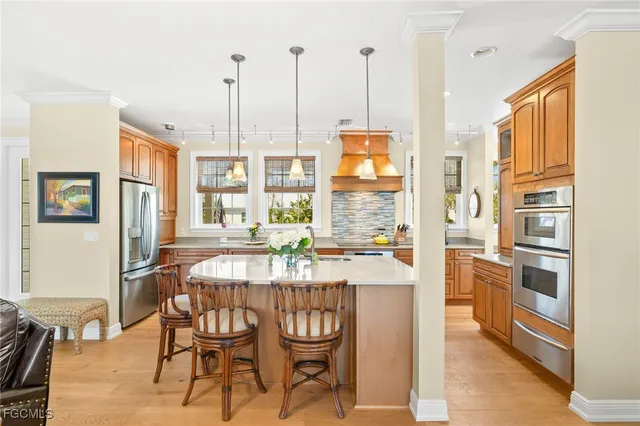 a kitchen with stainless steel appliances kitchen island granite countertop a table chairs and a refrigerator