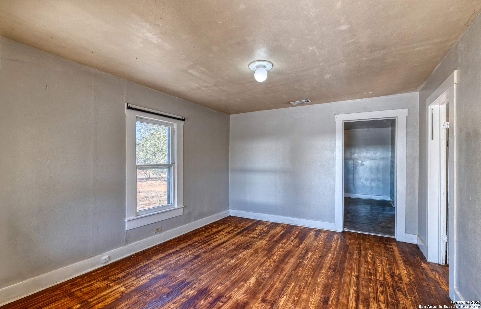 719 East Trinity Street Pearsall, TX 78061 - Photo 15 of 26 an empty room with wooden floor and windows