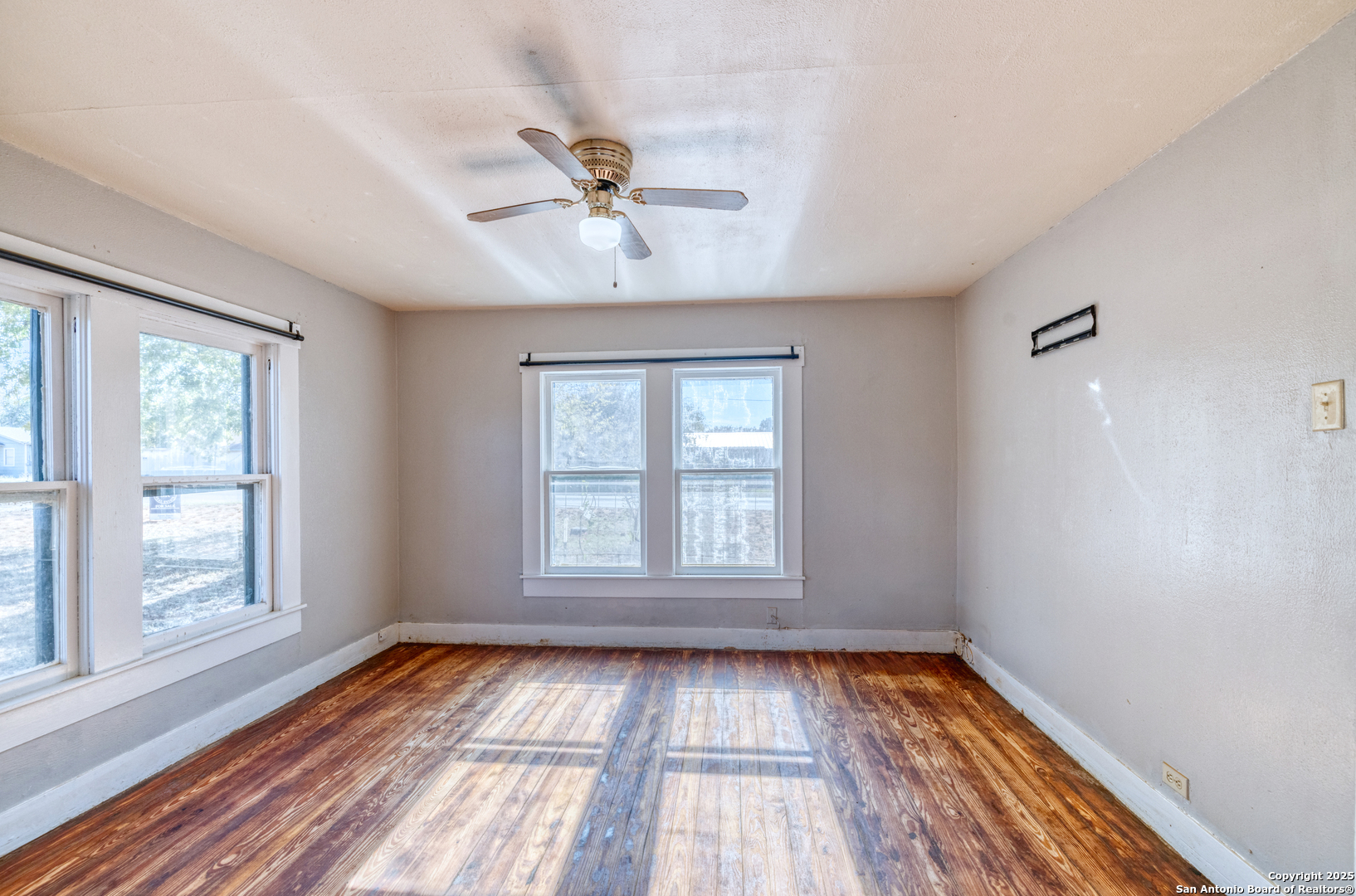 719 East Trinity Street Pearsall, TX 78061 - Photo 20 of 26 a view of an empty room with wooden floor and a window