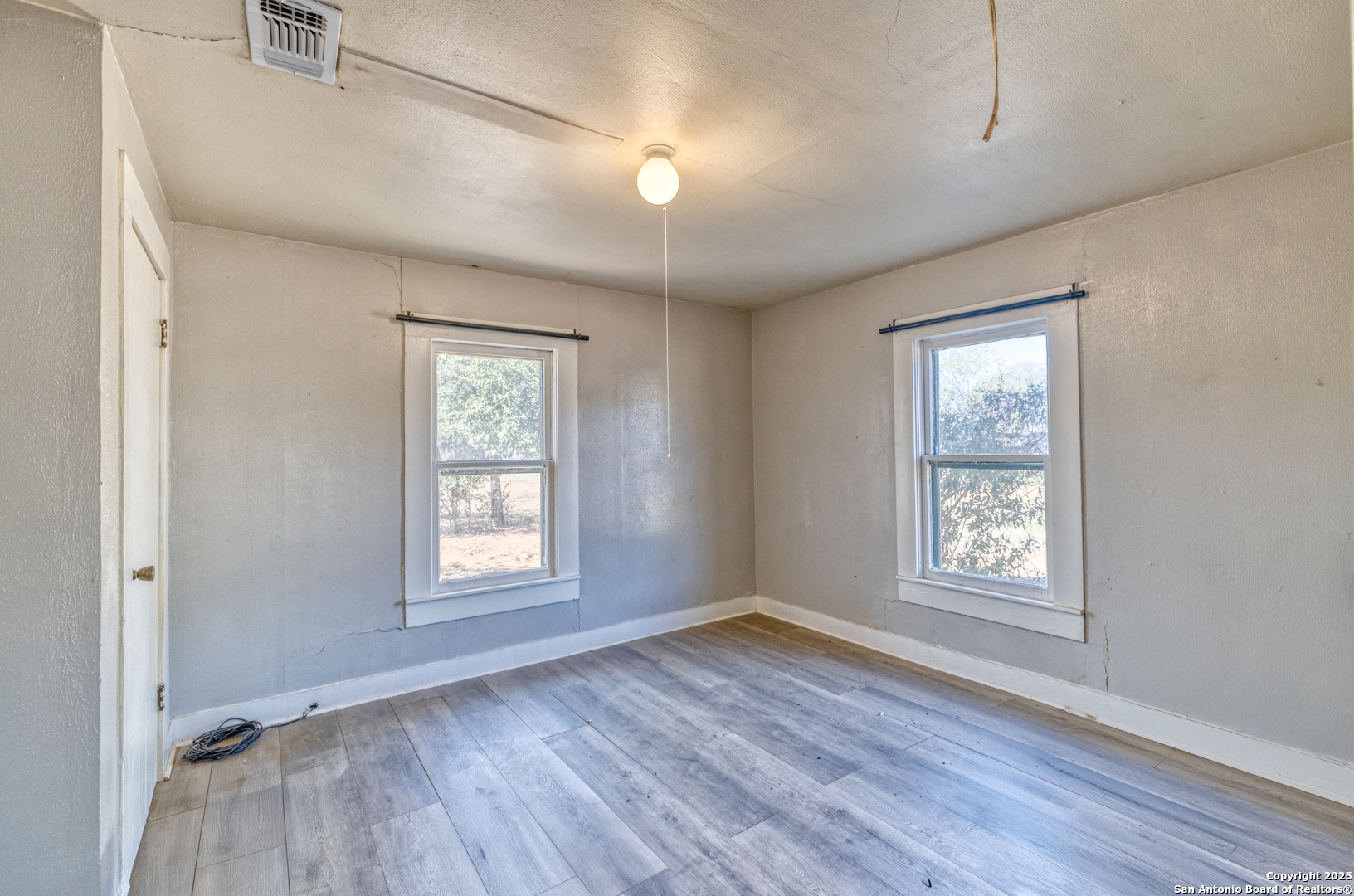 719 East Trinity Street Pearsall, TX 78061 - Photo 24 of 26 an empty room with wooden floor and window