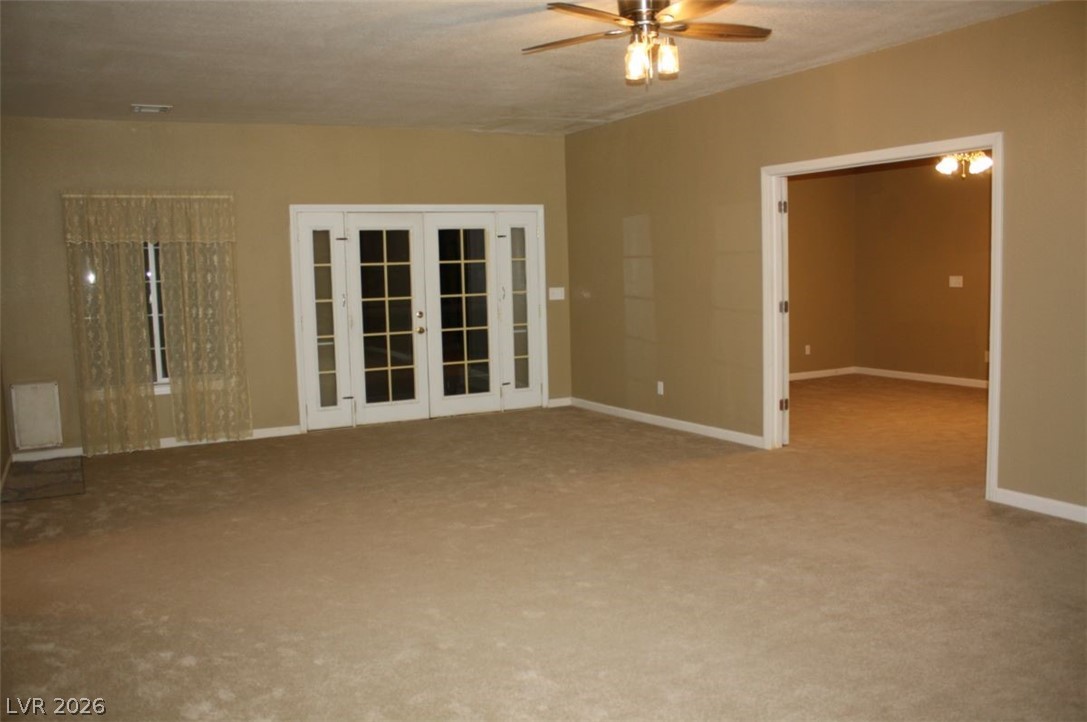 1101 East Blosser Ranch Road Pahrump, NV 89060 - Photo 14 of 50 Unfurnished Living / Family / Great room featuring french doors, ceiling fan, and carpet flooring