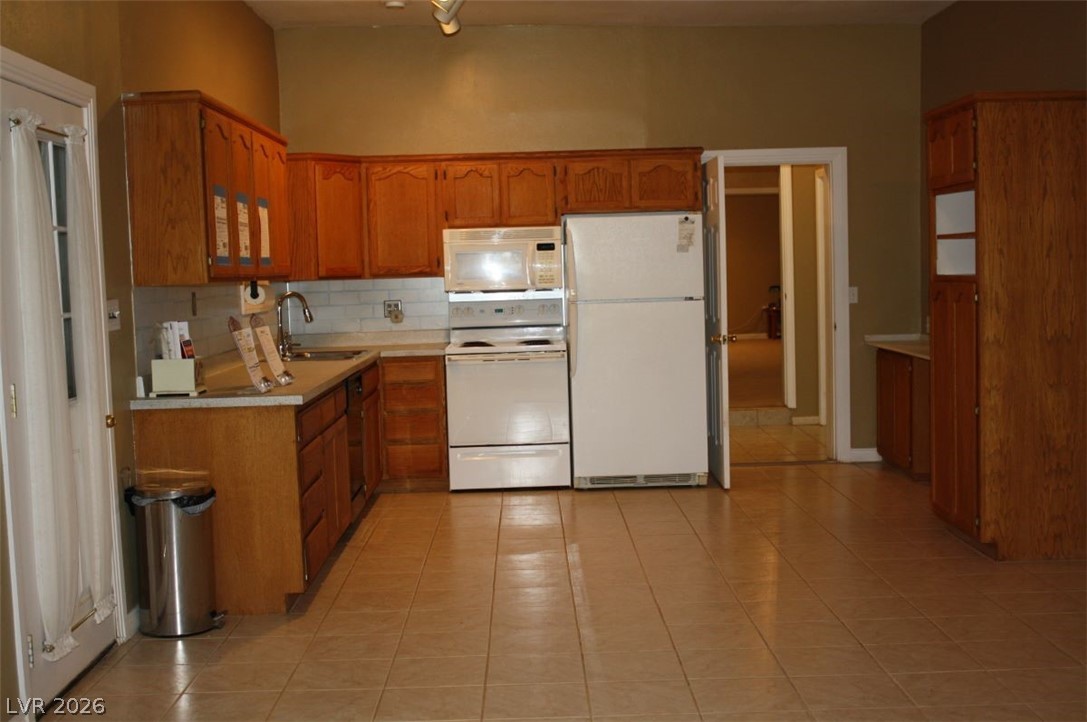 1101 East Blosser Ranch Road Pahrump, NV 89060 - Photo 4 of 50 Kitchen featuring light countertops, white appliances, wood finish cabinetry, tasteful backsplash, and light tile patterned floors