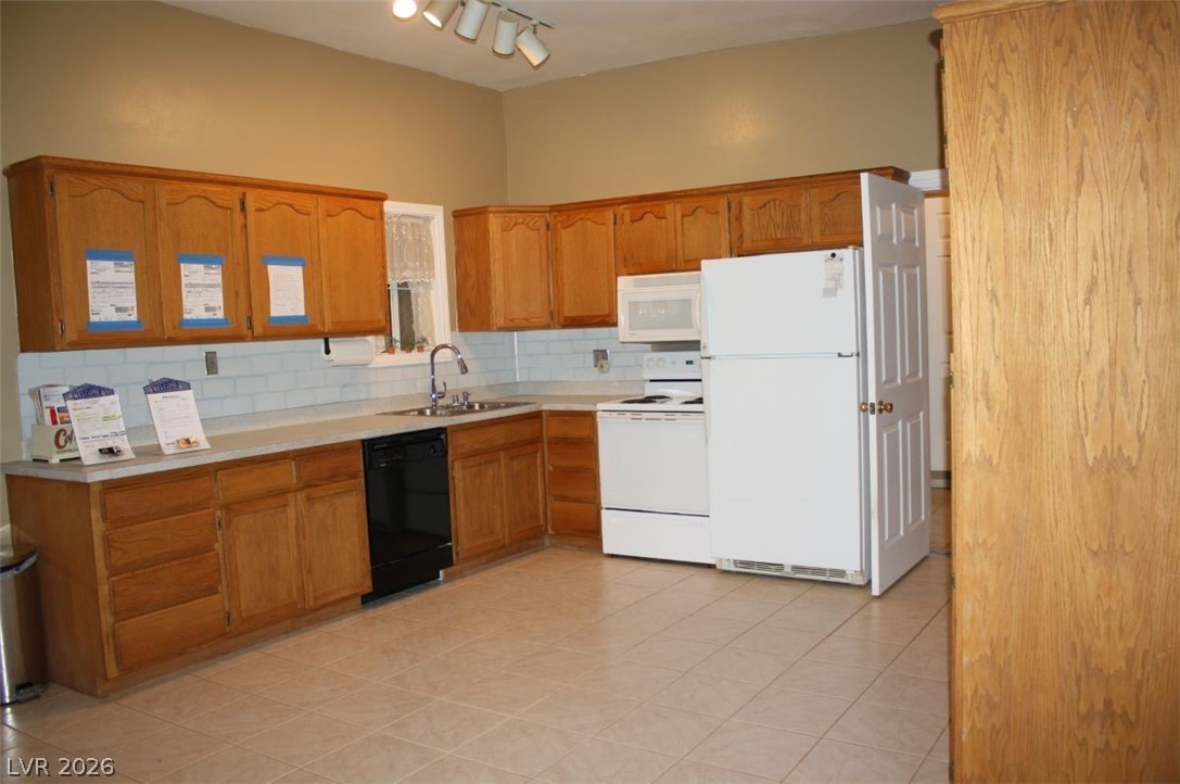 1101 East Blosser Ranch Road Pahrump, NV 89060 - Photo 5 of 50 Kitchen featuring white appliances, light countertops, decorative backsplash, wood finish cabinets, and light tile patterned floors