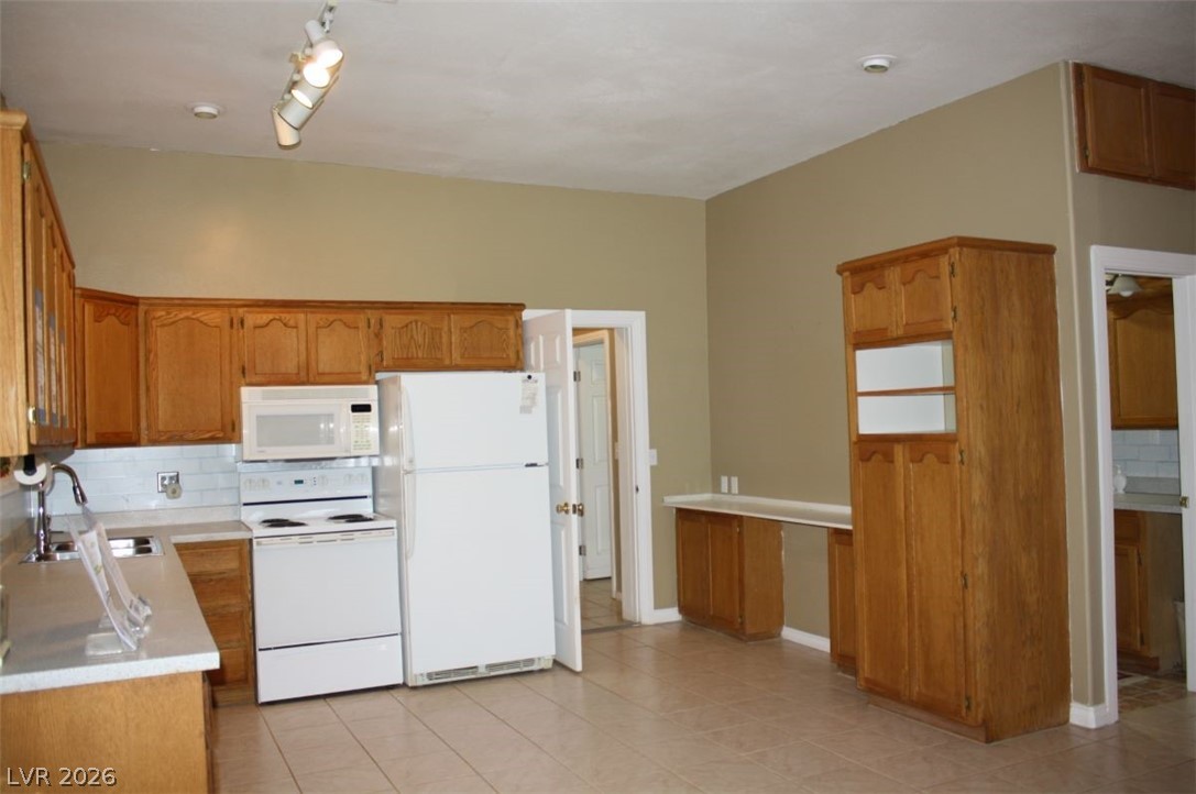 1101 East Blosser Ranch Road Pahrump, NV 89060 - Photo 6 of 50 Kitchen with backsplash, white appliances, light countertops, and wood finish cabinetry
