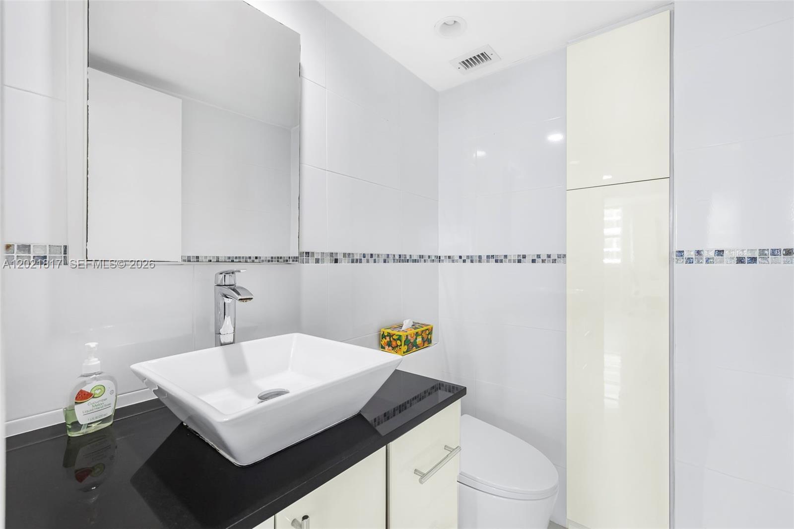 9511 Collins Avenue, Unit 1202 Surfside, FL 33154 - Photo 9 of 16 a bathroom with a sink toilet and a mirror