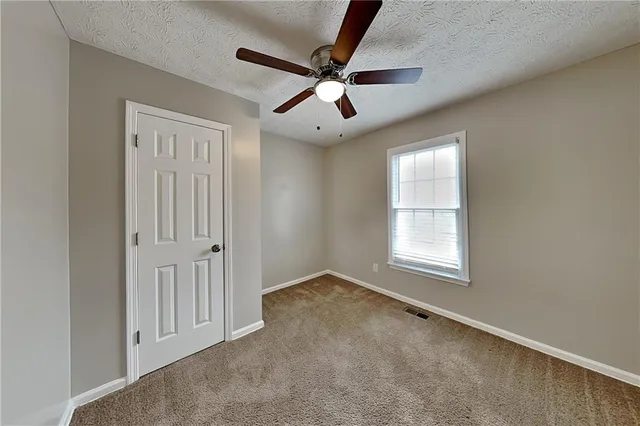 an empty room with ceiling fan and windows