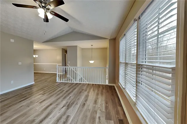 a view of a room with wooden floor fan and windows