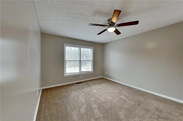 an empty room with ceiling fan and windows