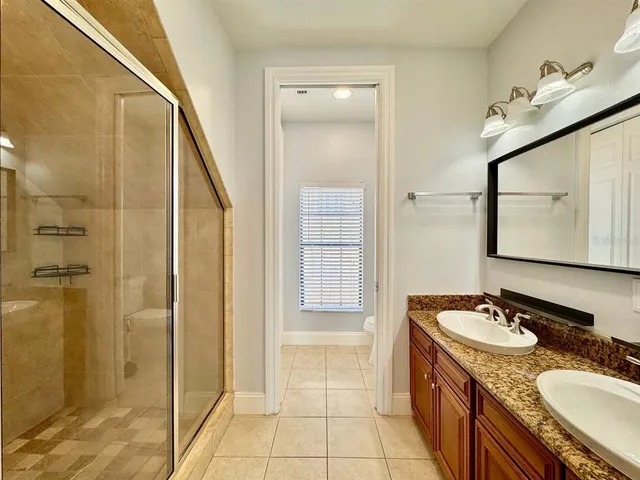 a bathroom with a granite countertop sink a mirror and shower