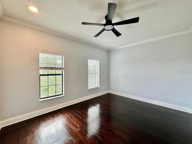 a view of empty room with wooden floor and fan