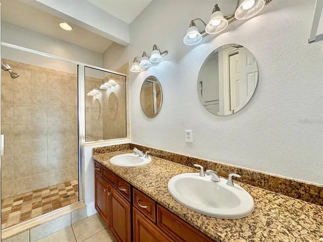 a bathroom with a granite countertop double vanity sink and a mirror