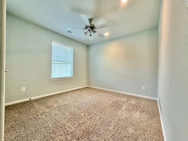 an empty room with a chandelier fan and windows