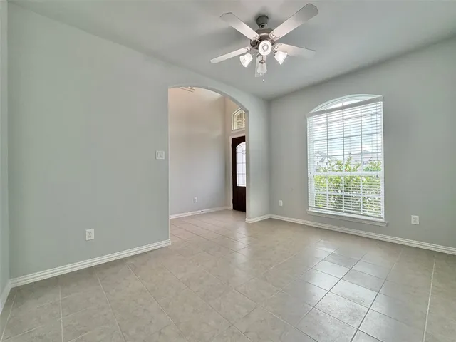 an empty room with chandelier fan and windows