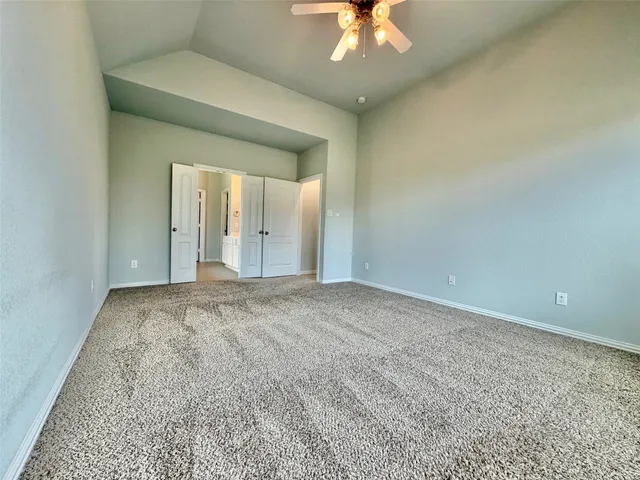 an empty room with a chandelier fan and windows