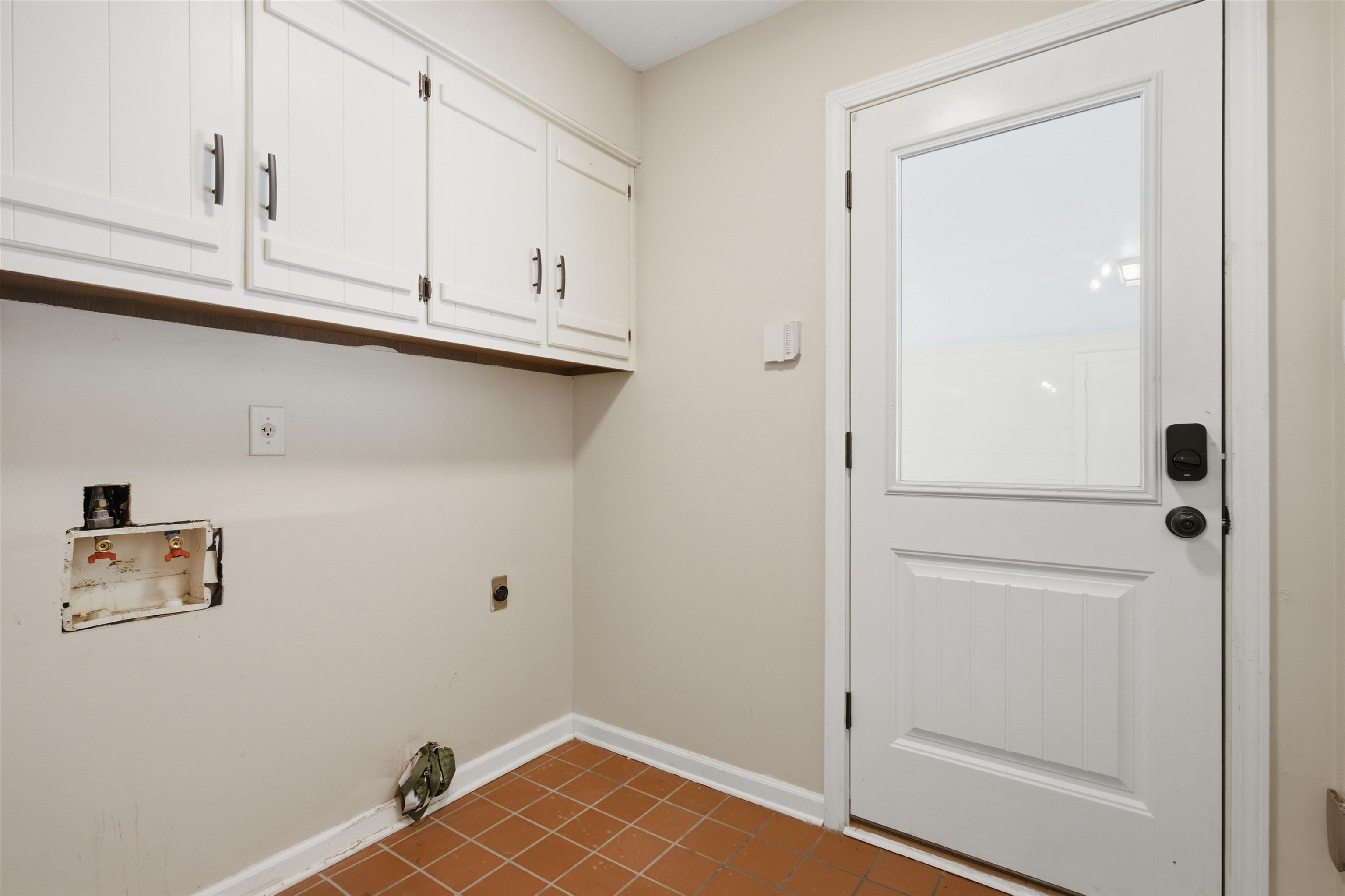 1370 North Reid Hooker Road Eads, TN 38028 - Photo 24 of 39 Utility area featuring terra cotta tile flooring, white shaker-style cabinetry with dark hardware, and a white paneled door with a partial glass insert
