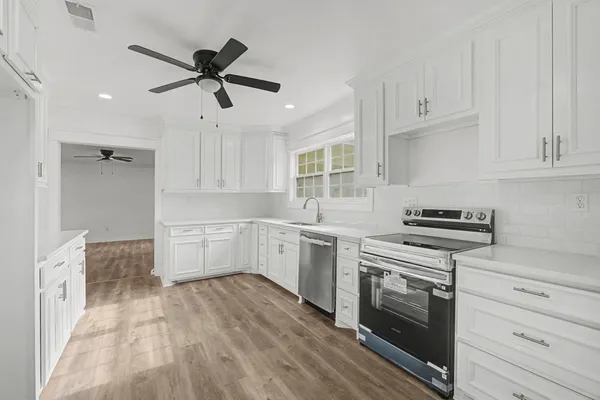 a kitchen with cabinets wooden floor and stainless steel appliances