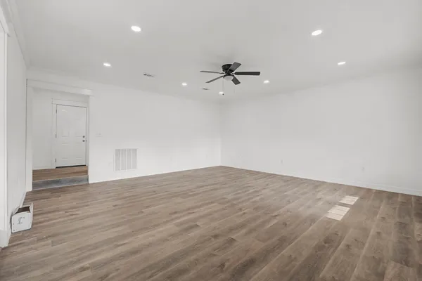 a view of empty room with wooden floor and ceiling fan