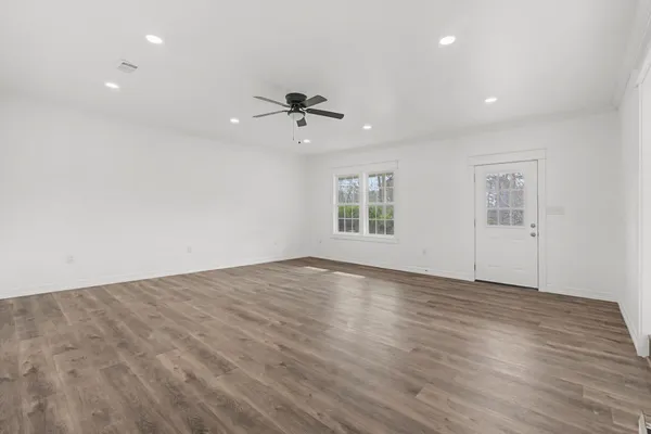 a view of an empty room with a window and wooden floor
