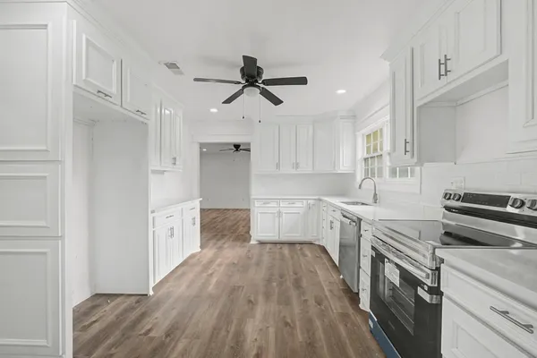 a kitchen with cabinets wooden floor and stainless steel appliances