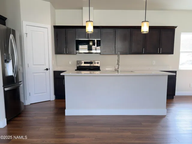 a kitchen with stainless steel appliances granite countertop a refrigerator a sink a stove and oven