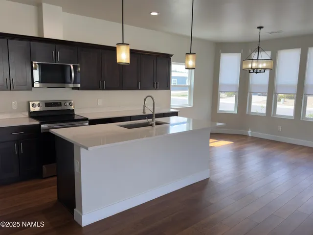 a kitchen with stainless steel appliances a sink a stove a refrigerator and cabinets