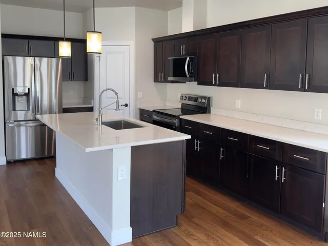a kitchen with stainless steel appliances granite countertop a sink a stove and a wooden floor