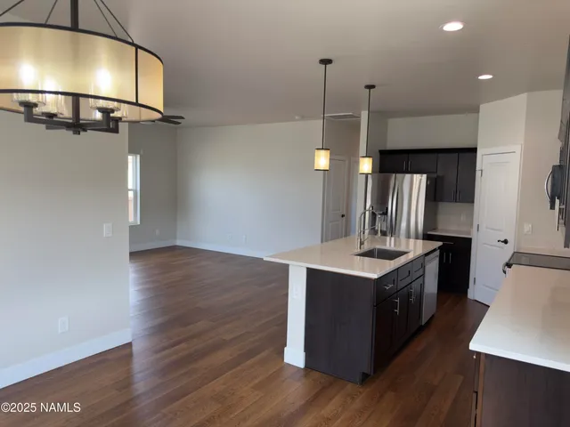 a kitchen with stainless steel appliances granite countertop a refrigerator a stove top oven a sink and dishwasher with wooden floor