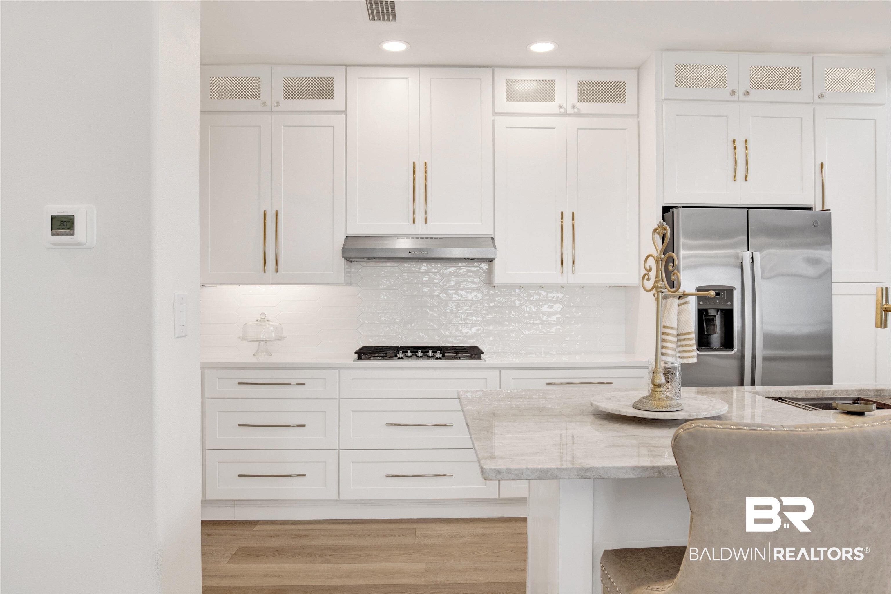 30351 River Road Orange Beach, AL 36561 - Photo 10 of 44 Modern kitchen featuring white cabinetry with gold-tone hardware, a stainless steel gas cooktop, and a stainless steel range hood