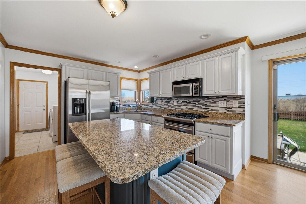 9741 Whitehall Garden Munster, IN 46321 - Photo 14 of 30 a kitchen with stainless steel appliances granite countertop a kitchen island hardwood floor sink stove and granite counter top
