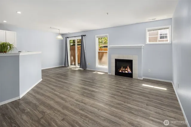 a view of an empty room with wooden floor fireplace and a window