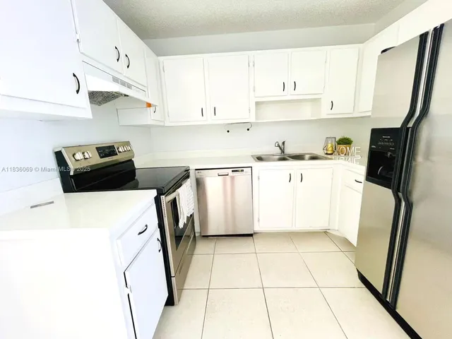 a kitchen with stainless steel appliances a refrigerator sink and white cabinets